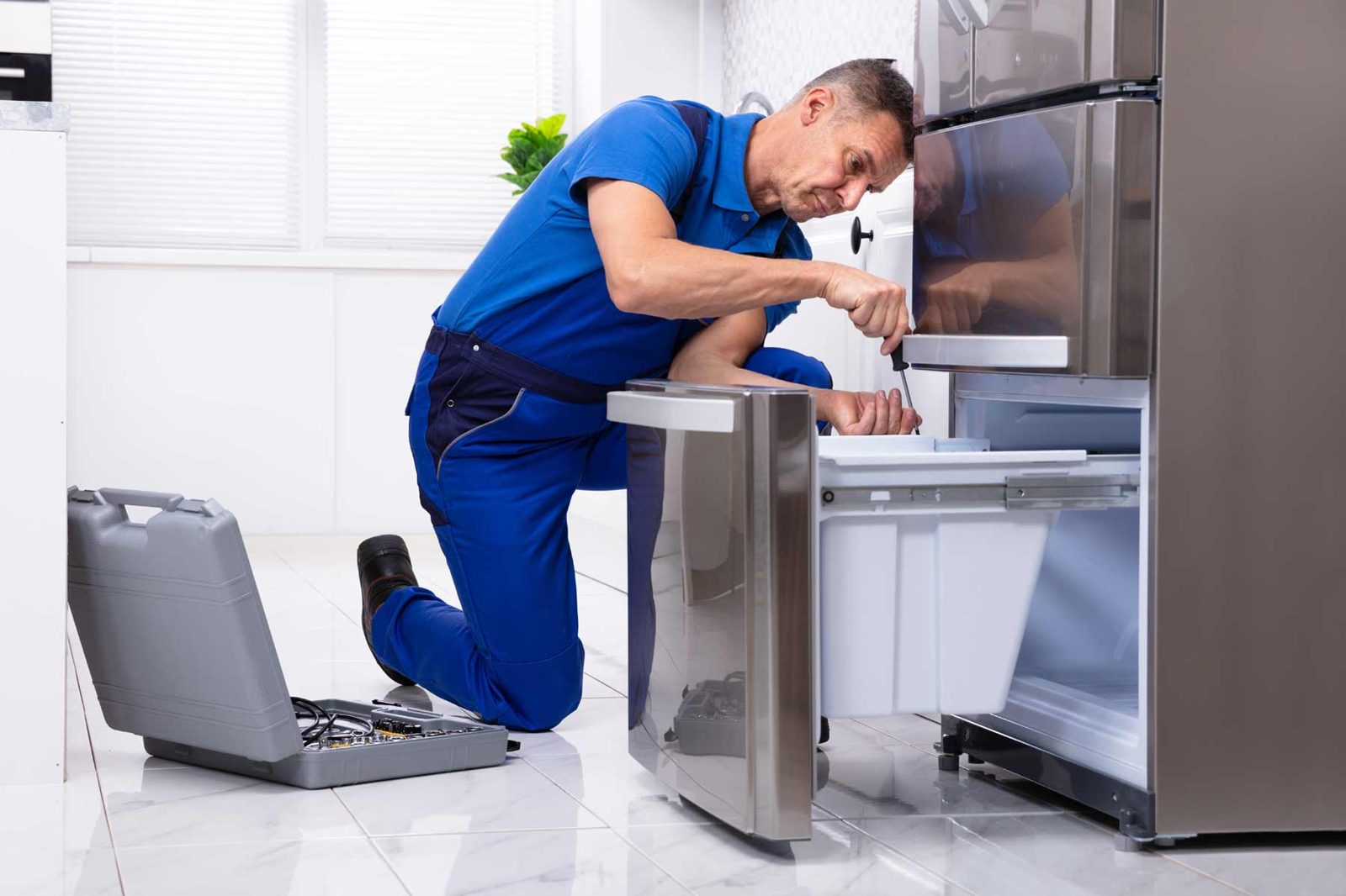 Technician working on the interior panel of a stainless steel refrigerator