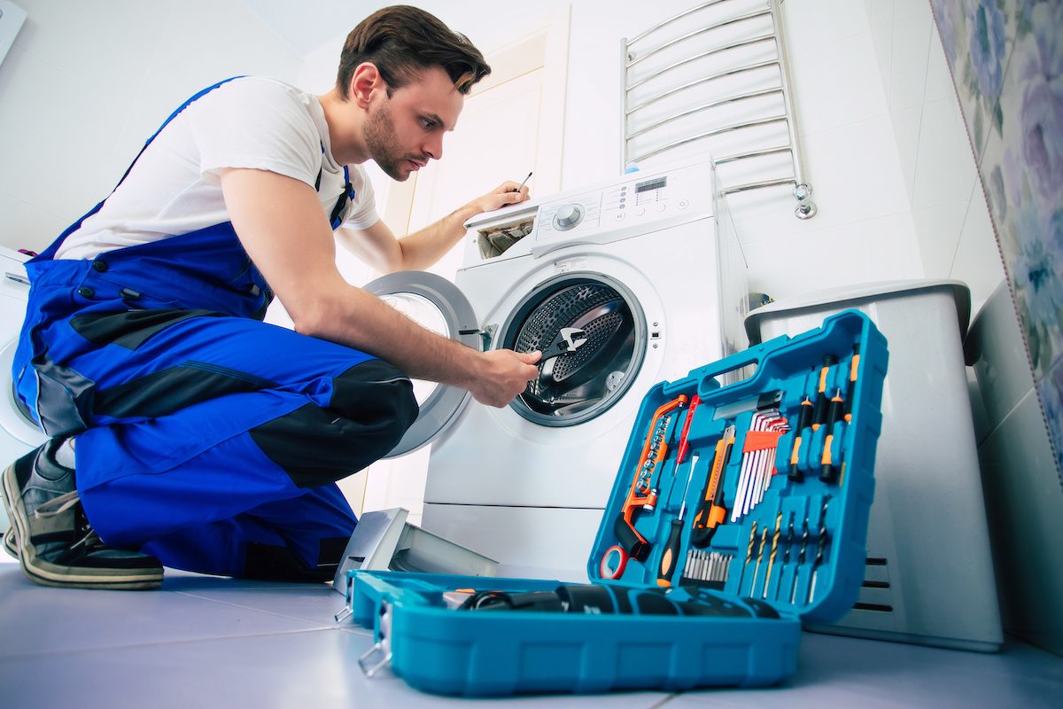 Appliance technician carrying a parts case toward a kitchen
